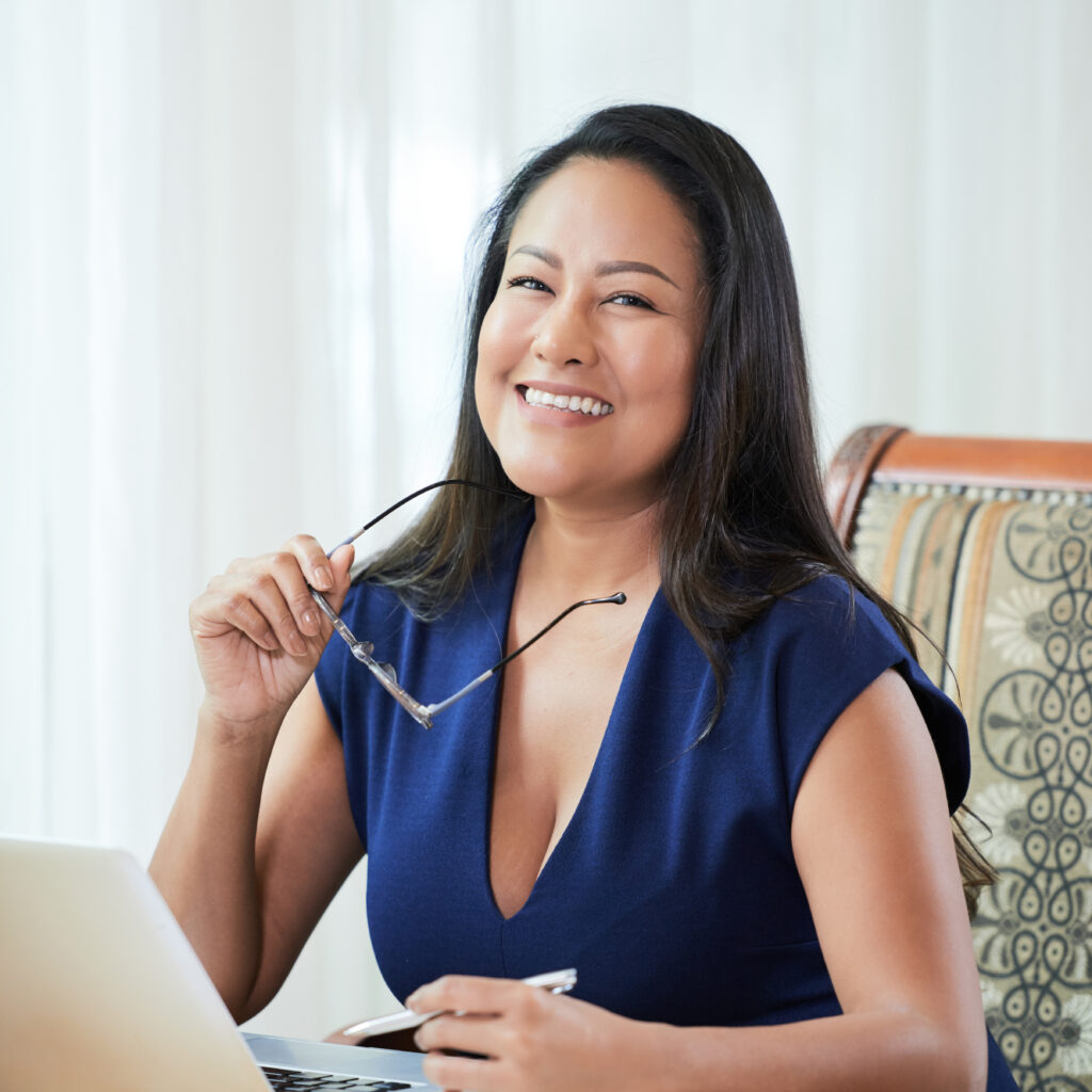 Happy ethnic businesswoman at table in office